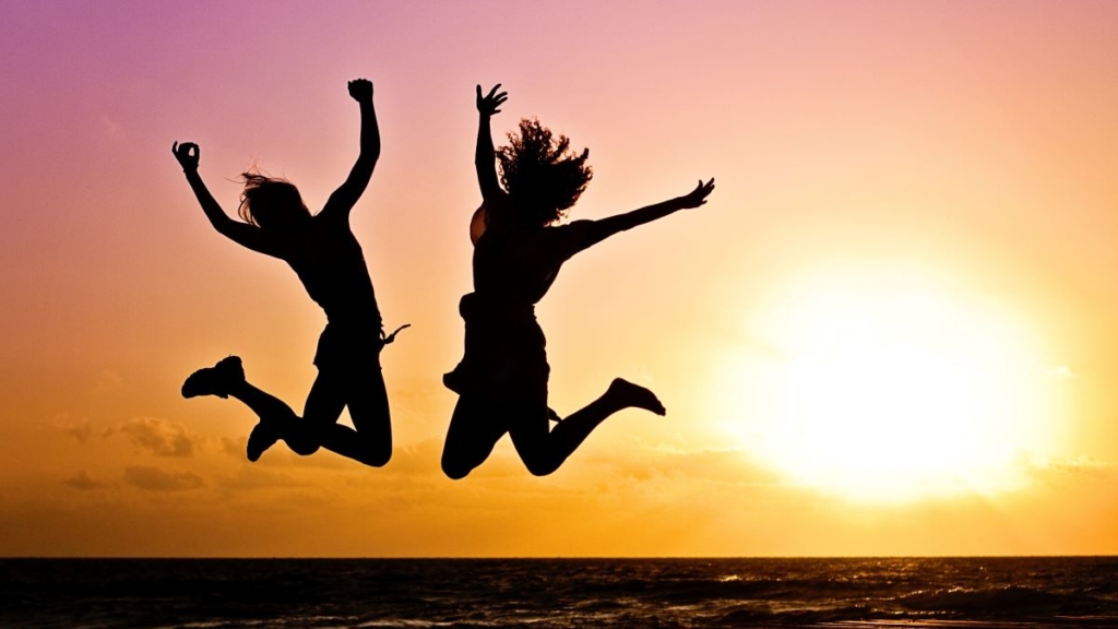 2 Personen springen Glücklich in die Luft vor einem Sonnenuntergang